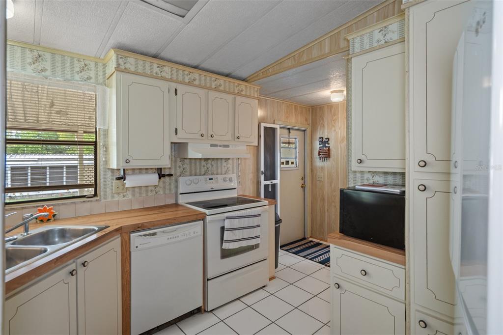12306 Club House Road Brooksville, FL 34613 - Photo 5 of 36 a kitchen with white cabinets and white appliances