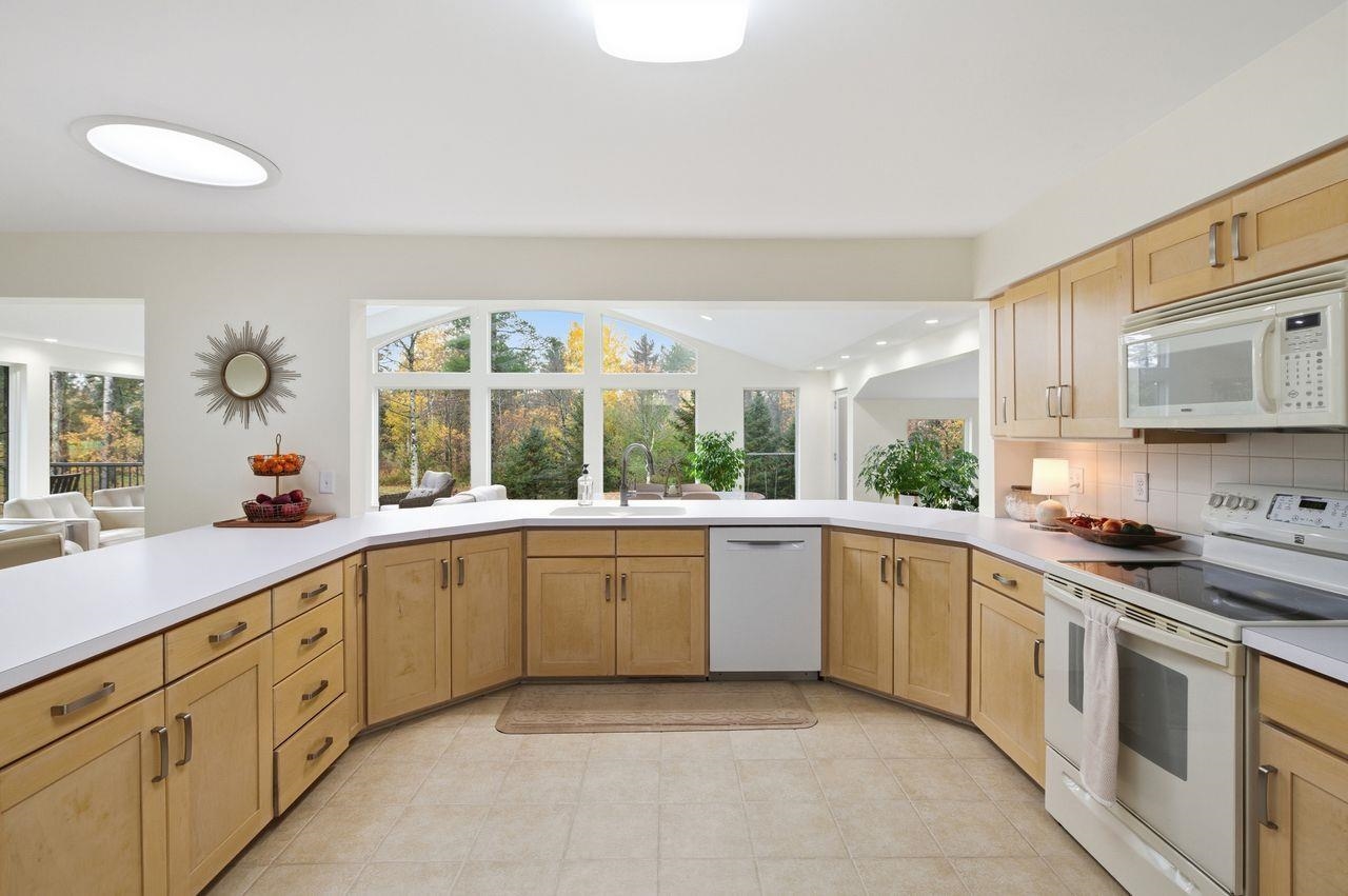64903 Charles Johnson Road Ashland, WI 54806 - Photo 12 of 52 Kitchen with light brown cabinets, white appliances, light countertops, decorative backsplash, and healthy amount of natural light
