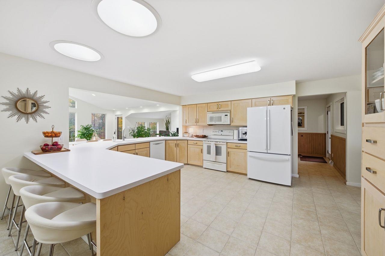 64903 Charles Johnson Road Ashland, WI 54806 - Photo 14 of 52 Kitchen featuring a peninsula, light brown cabinets, white appliances, light countertops, and a kitchen breakfast bar