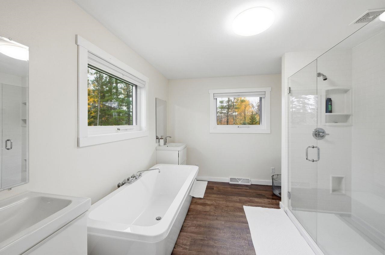 64903 Charles Johnson Road Ashland, WI 54806 - Photo 19 of 52 Full bath with two vanities, a stall shower, healthy amount of natural light, and dark wood-style flooring