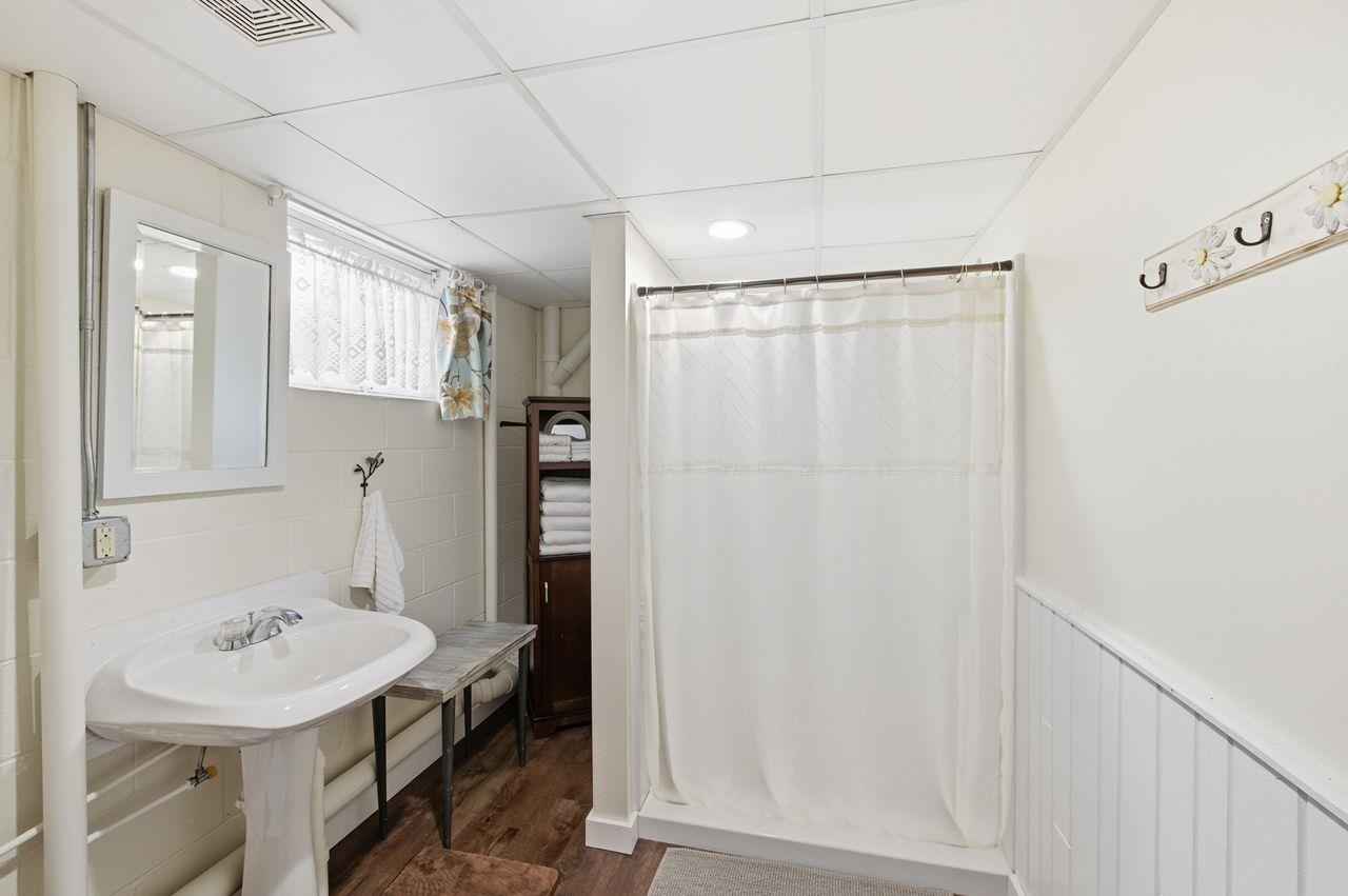 64903 Charles Johnson Road Ashland, WI 54806 - Photo 31 of 52 Bathroom with a stall shower, a drop ceiling, dark wood-type flooring, and a wainscoted wall