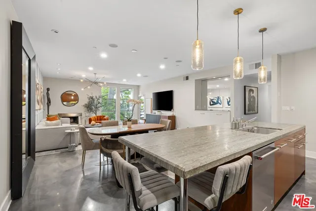 a view of a dining room and livingroom with furniture wooden floor a rug a flat screen tv a rug and a chandelier