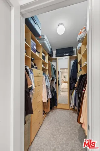 a view of walk in closet with clothes and shoes