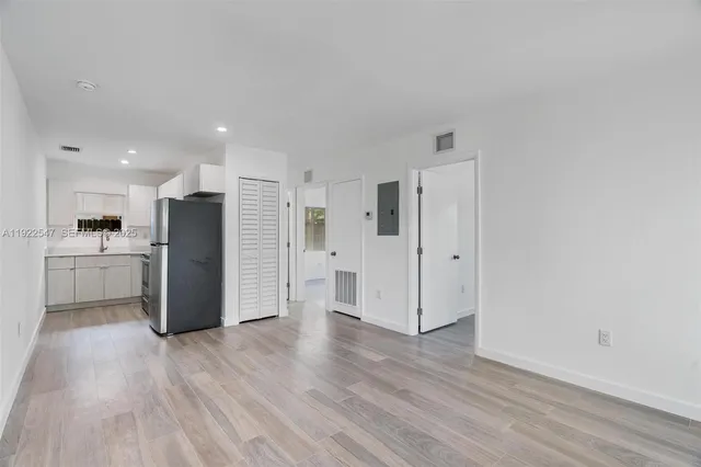 a view of a kitchen with a refrigerator and wooden floor
