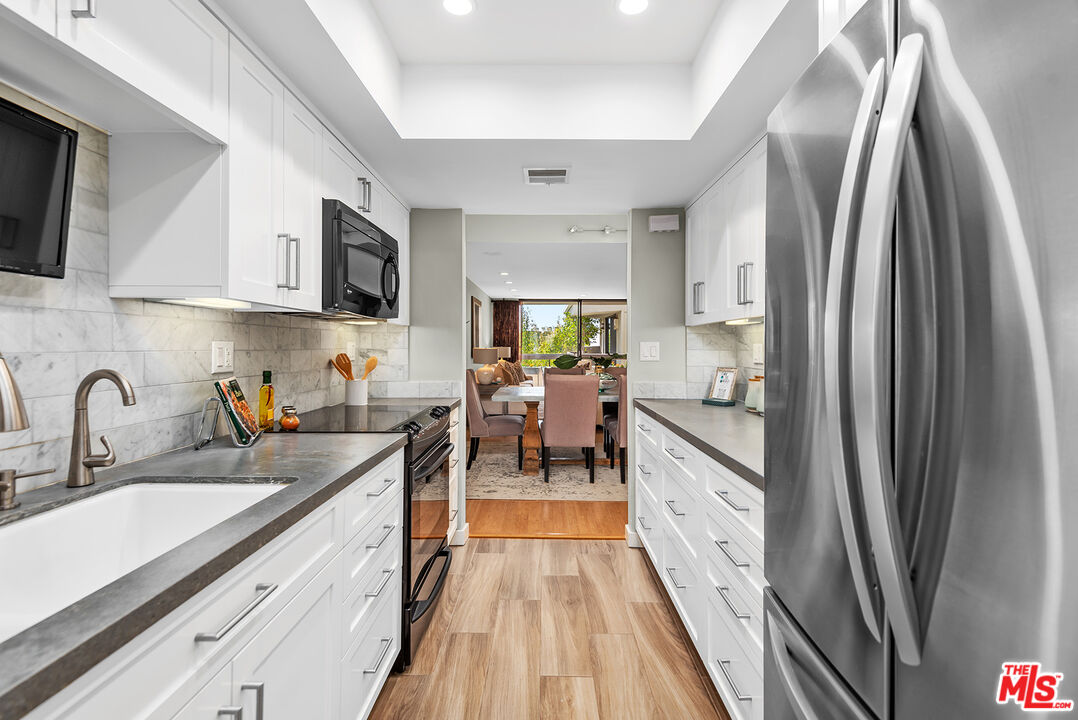 851 North Kings Road, Unit 307 West Hollywood, CA 90069 - Photo 15 of 38 a kitchen with stainless steel appliances a refrigerator sink and white cabinets