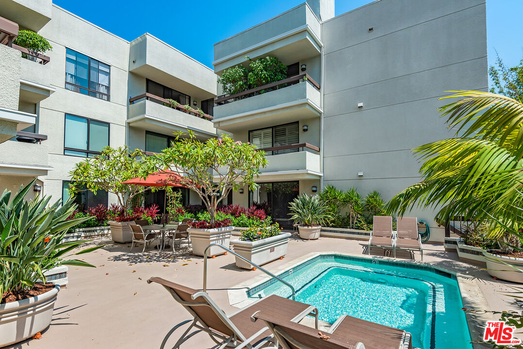 851 North Kings Road, Unit 307 West Hollywood, CA 90069 - Photo 37 of 38 a view of a patio with couches table and chairs under an umbrella with potted plants