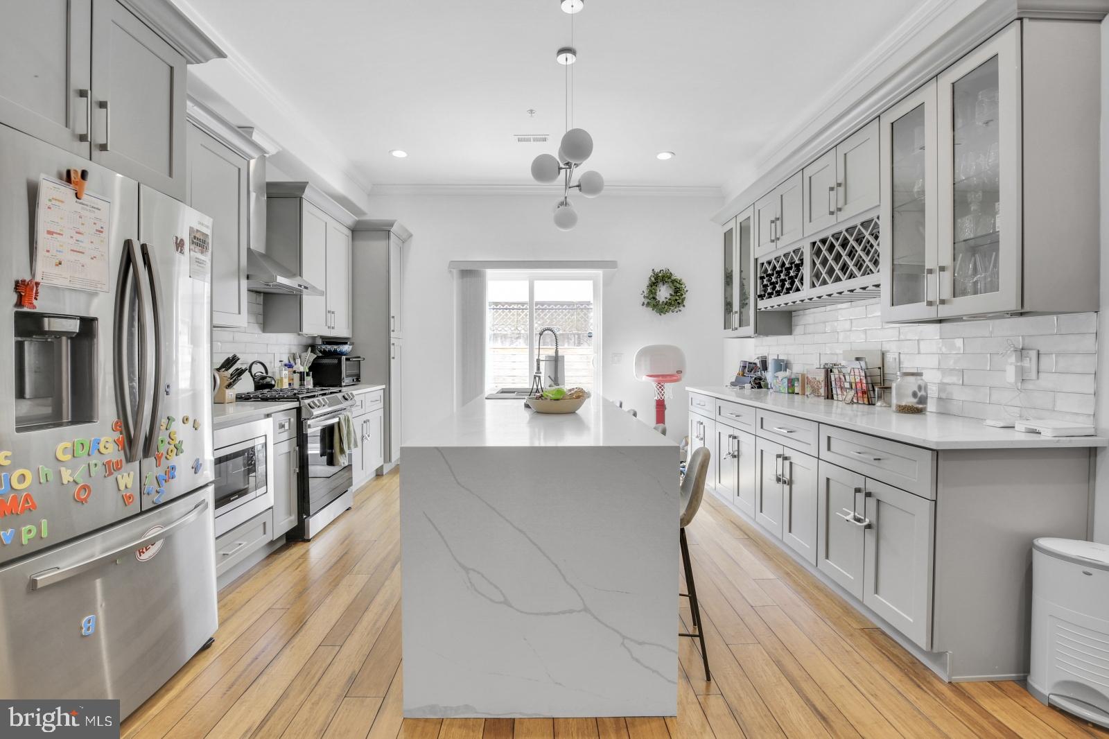 a kitchen with stainless steel appliances a stove a sink dishwasher a refrigerator and white cabinets with wooden floor