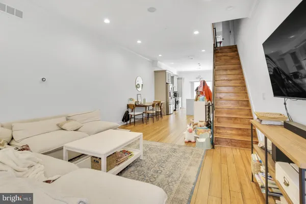 a living room with couches and kitchen view with wooden floor