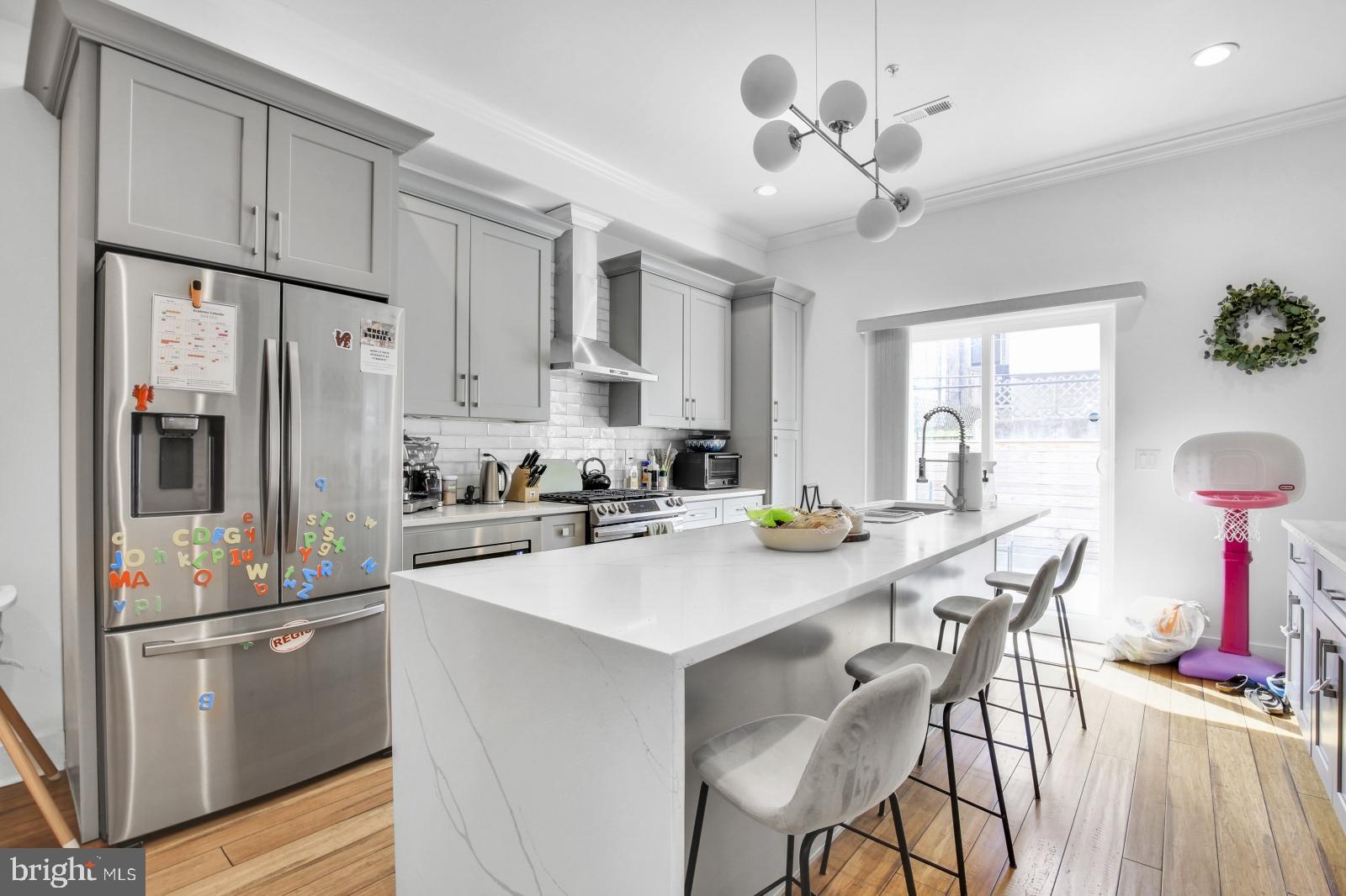 2604 Reed Street Philadelphia, PA 19146 - Photo 5 of 32 a kitchen with stainless steel appliances a refrigerator a stove a sink a dining table and chairs with wooden floor