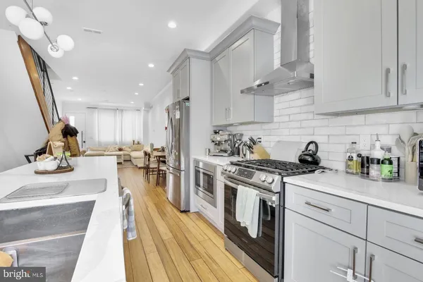 a kitchen with stainless steel appliances granite countertop a stove a sink dishwasher and white cabinets with wooden floor