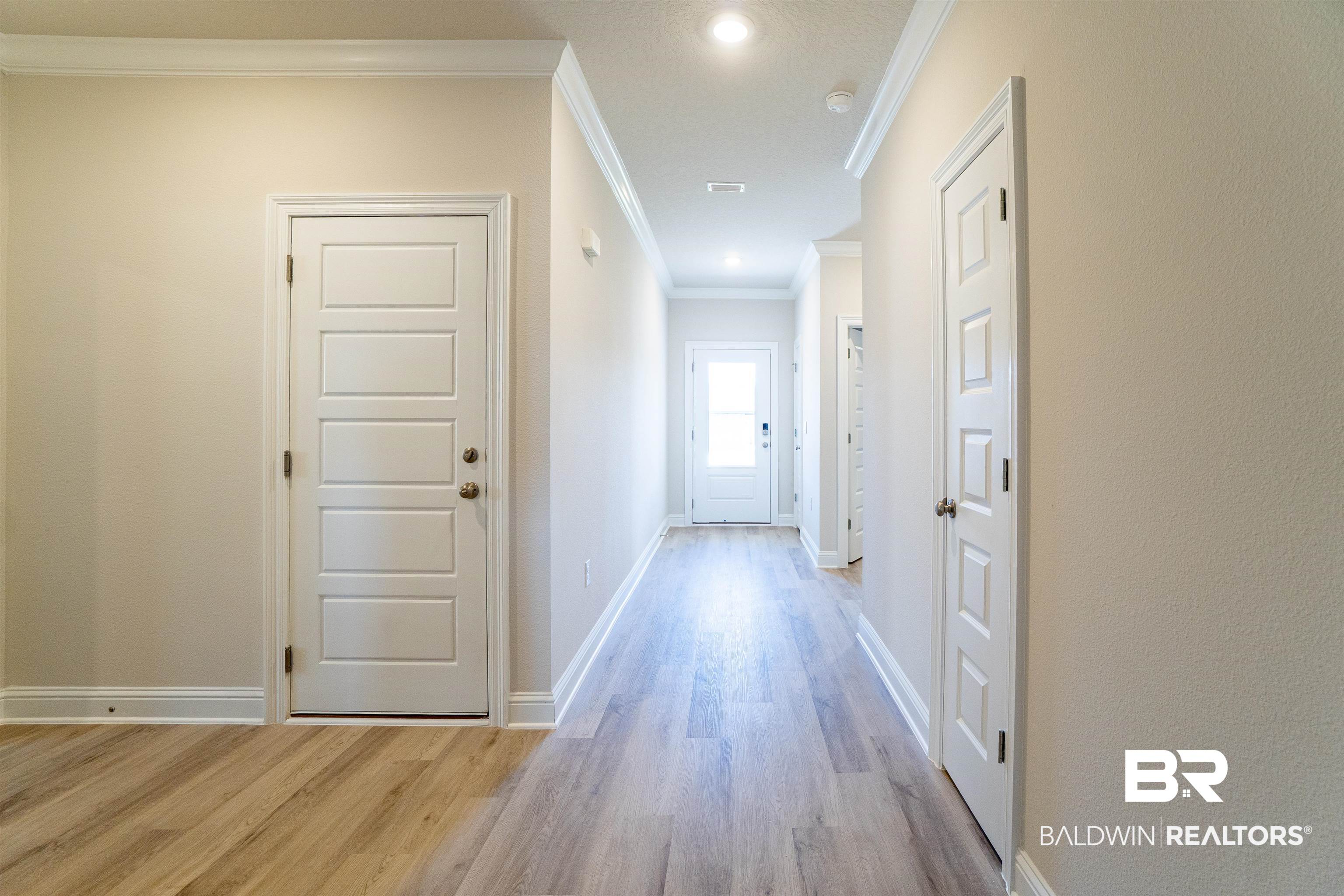 1073 Hayward Loop Foley, AL 36535 - Photo 6 of 18 Long hallway featuring light wood-finish flooring, neutral-toned walls, and white crown molding
