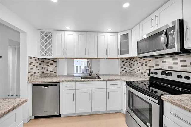 a kitchen with granite countertop a stove sink and microwave