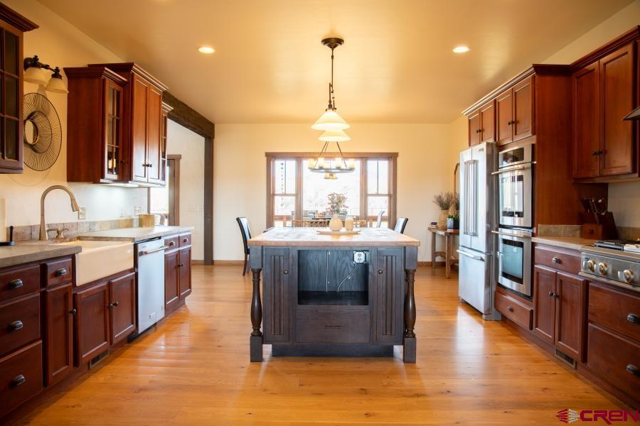 66961 Solar Road Montrose, CO 81403 - Photo 15 of 44 a kitchen with stainless steel appliances granite countertop a stove a sink dishwasher a refrigerator and a dining table with wooden floor