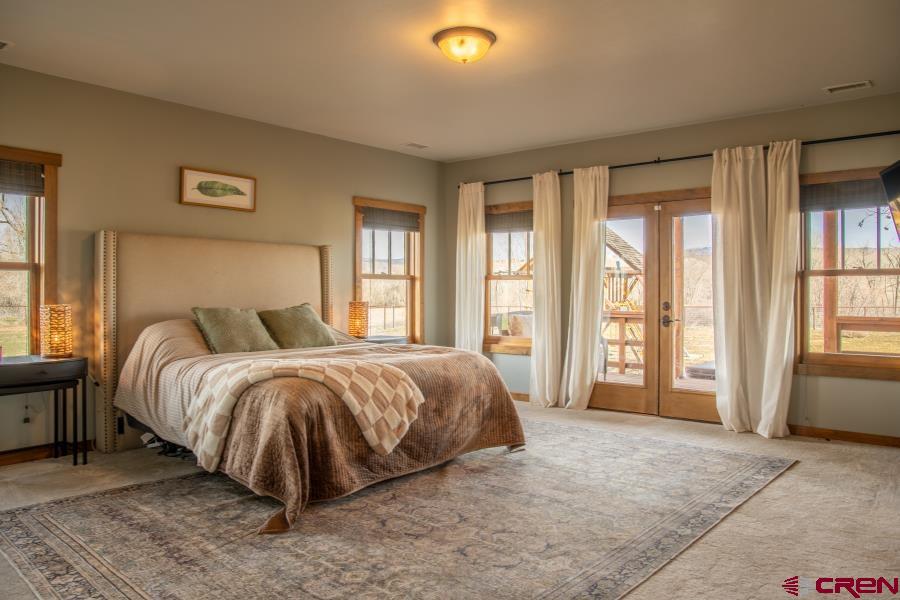 66961 Solar Road Montrose, CO 81403 - Photo 21 of 44 a spacious bedroom with a bed and large windows