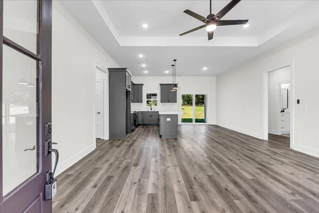 a view of a hallway with wooden floor and a kitchen