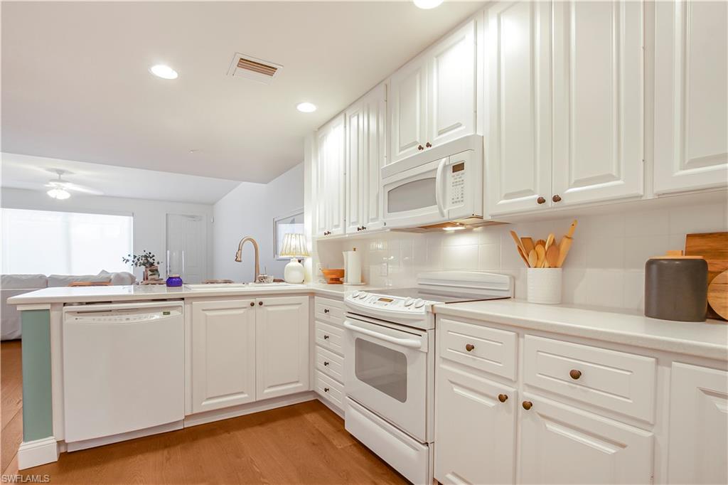 7201 Bellini Way Naples, FL 34114 - Photo 6 of 39 a kitchen with white cabinets and white appliances