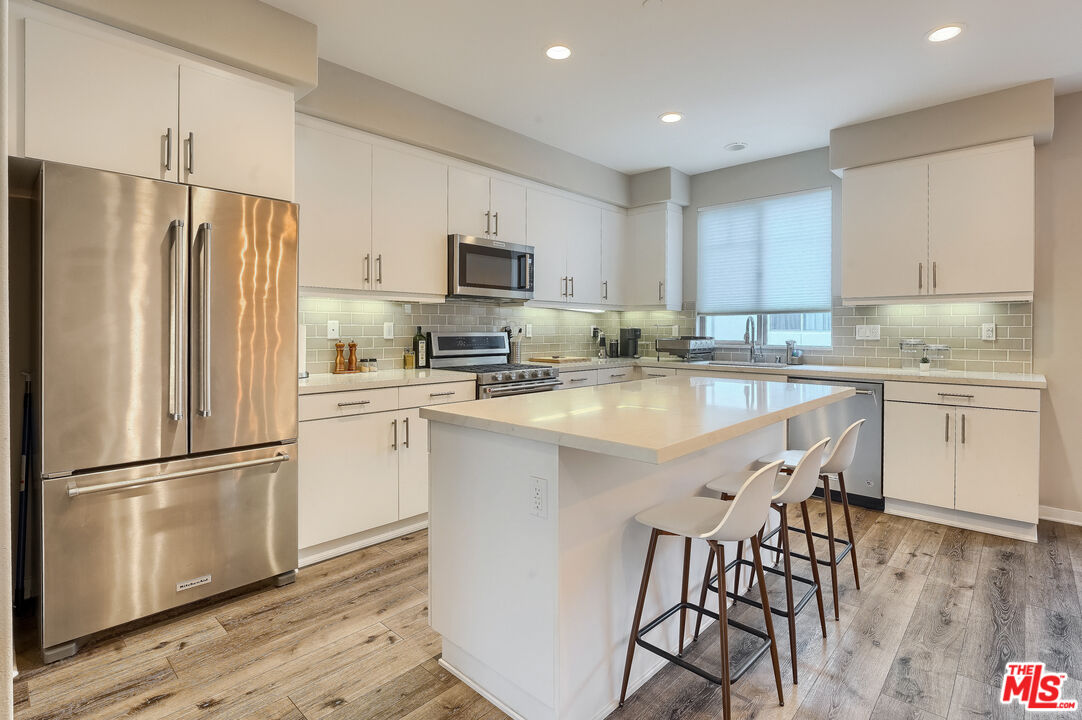 237 Magnet Irvine, CA 92618 - Photo 5 of 34 a kitchen with stainless steel appliances granite countertop a refrigerator a sink dishwasher a stove and white cabinets with wooden floor