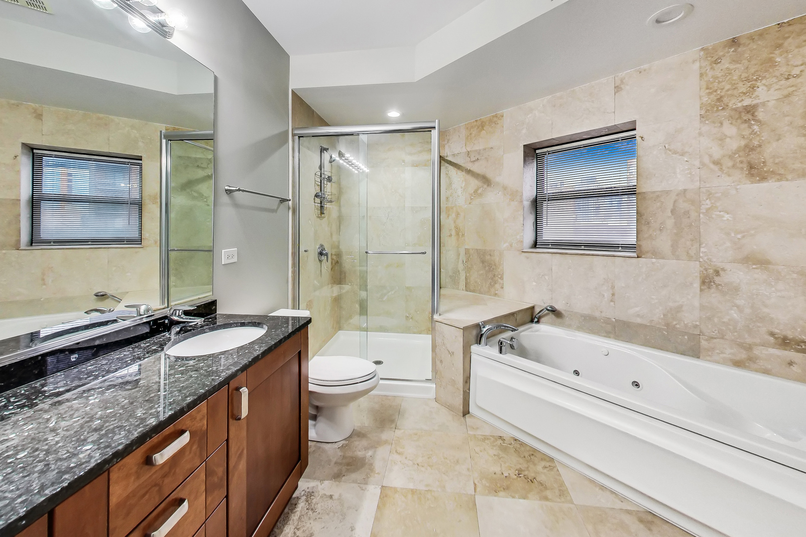 651 North Milwaukee Avenue, Unit 304 Chicago, IL 60642 - Photo 17 of 33 a bathroom with a granite countertop sink a toilet a mirror a bathtub and shower