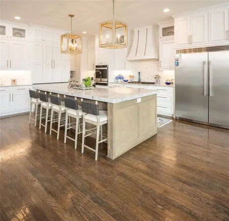 a kitchen with stainless steel appliances a dining table chairs sink and cabinets