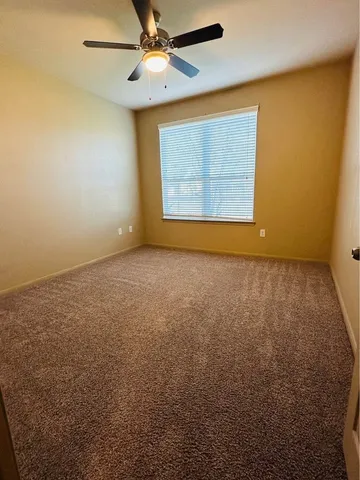 an empty room with a window and a ceiling fan