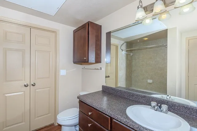 a bathroom with a granite countertop sink toilet a mirror and shower
