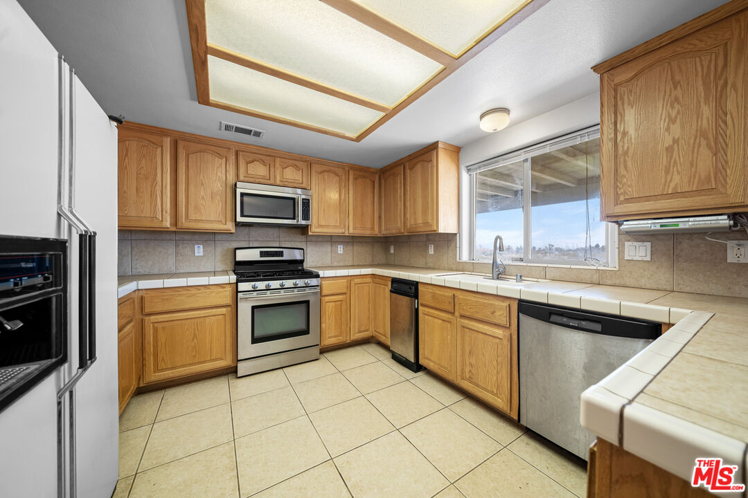 11635 Lebec Road Phelan, CA 92371 - Photo 13 of 35 a kitchen with granite countertop a stove top oven sink and cabinets