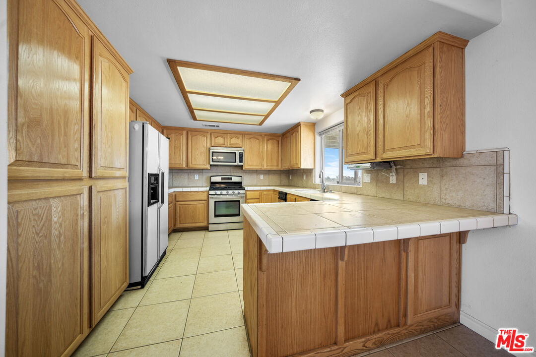 11635 Lebec Road Phelan, CA 92371 - Photo 14 of 35 a kitchen with stainless steel appliances granite countertop a sink a stove and a refrigerator