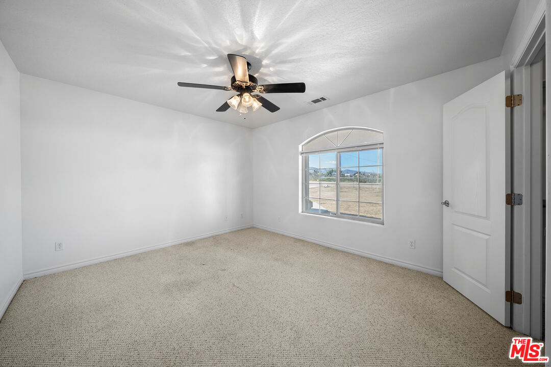 11635 Lebec Road Phelan, CA 92371 - Photo 23 of 35 an empty room with a chandelier fan and windows