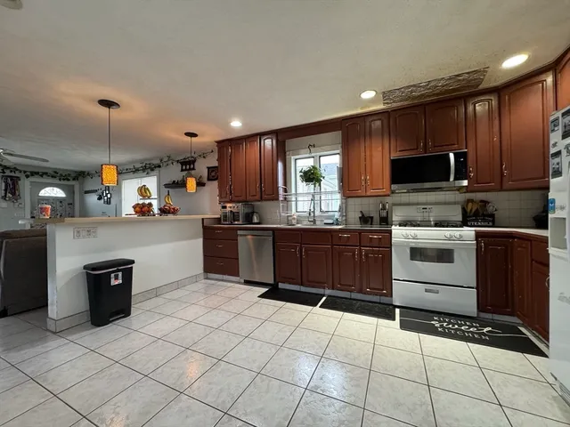 a kitchen with stainless steel appliances granite countertop a stove top oven a sink dishwasher and a refrigerator