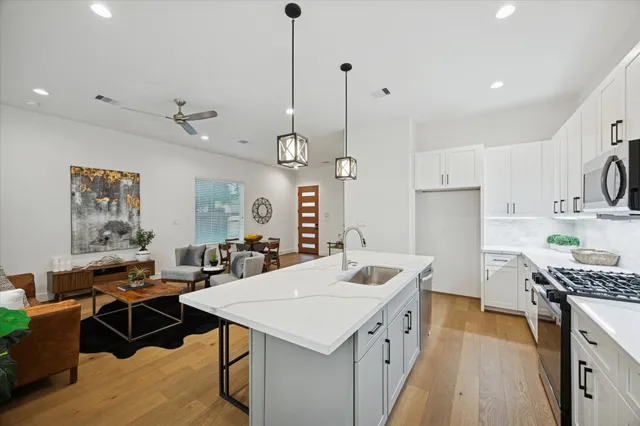 a kitchen with stainless steel appliances kitchen island a table chairs in it and wooden floors