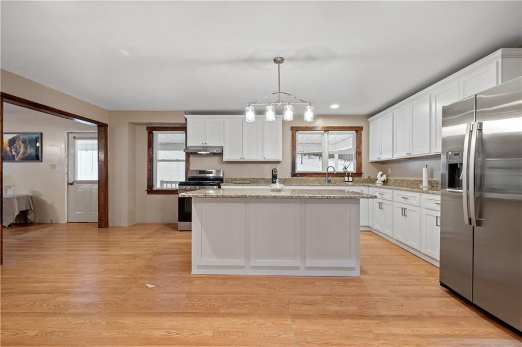 1575 Windows Road Smicksburg, PA 16256 - Photo 17 of 35 a large kitchen with kitchen island a stove a refrigerator a sink dishwasher and a fireplace with wooden floor