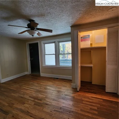 an empty room with wooden floor closet and windows