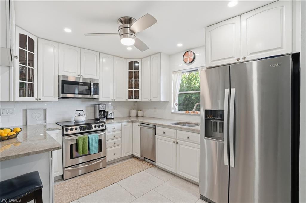 560 109th Avenue North Naples, FL 34108 - Photo 12 of 37 a kitchen with stainless steel appliances granite countertop a refrigerator a stove a sink and a microwave