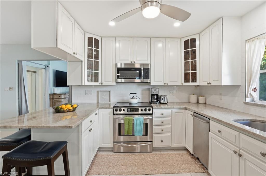 560 109th Avenue North Naples, FL 34108 - Photo 13 of 37 a kitchen with stainless steel appliances granite countertop a stove top oven a sink dishwasher and cabinets with wooden floor