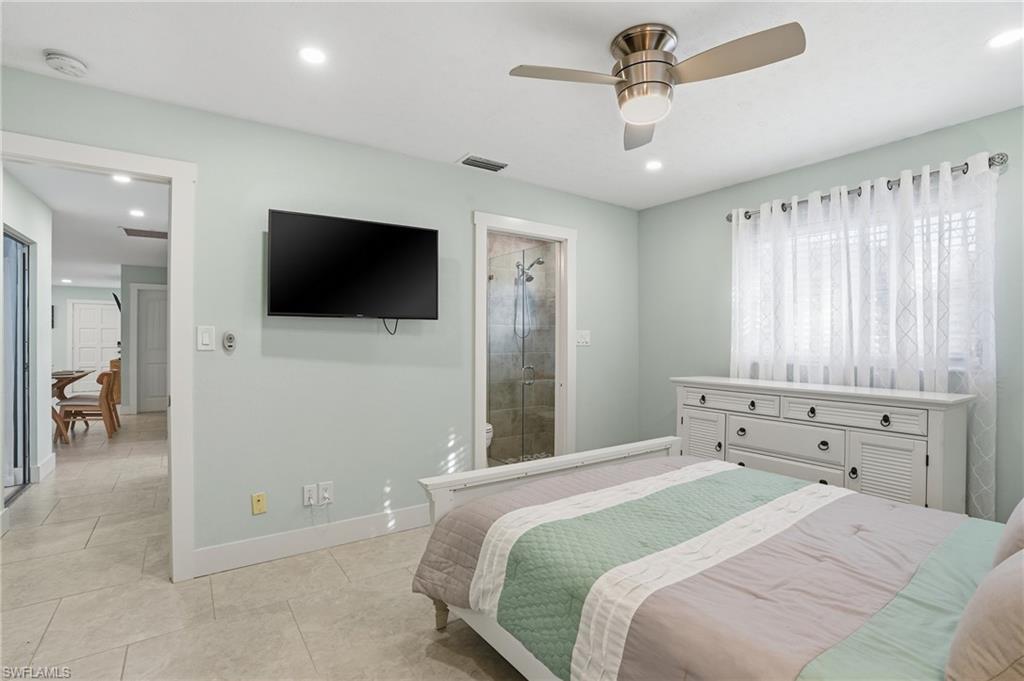 560 109th Avenue North Naples, FL 34108 - Photo 16 of 37 a bedroom with a bed and a flat tv screen on wall