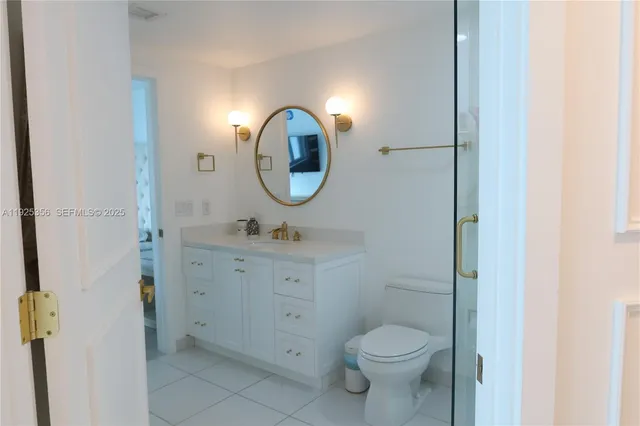 a bathroom with a toilet sink vanity granite and a mirror