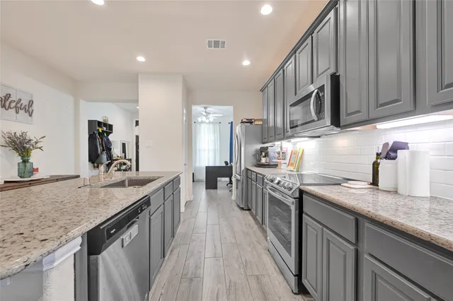 a kitchen with kitchen island granite countertop wooden cabinets a sink and a stove