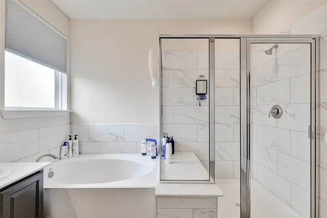 a bathroom with a double vanity sink mirror and a bathtub