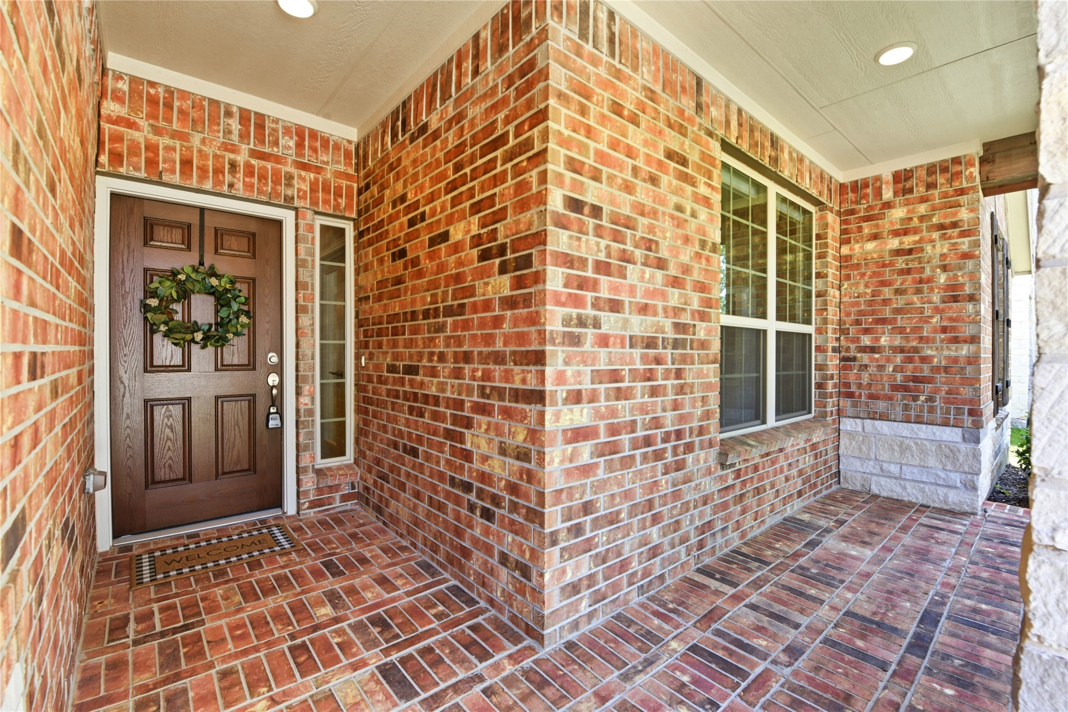 17834 Maple Ash Drive Spring, TX 77379 - Photo 5 of 50 This photo showcases a welcoming brick front porch with a wooden door. It features a large window, providing natural light, and a covered entryway that adds charm and protection from the elements.