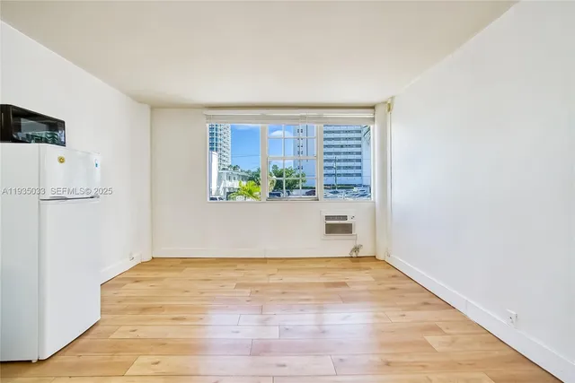a view of empty room with wooden floor and window