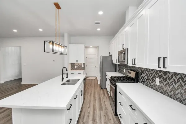 a kitchen with granite countertop a sink a counter top space stainless steel appliances and cabinets