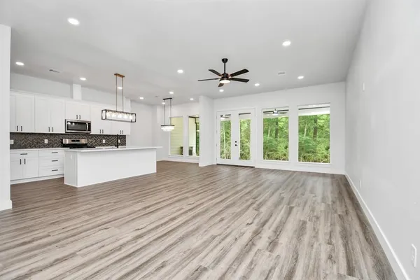 a view of an empty room with a window and wooden floor
