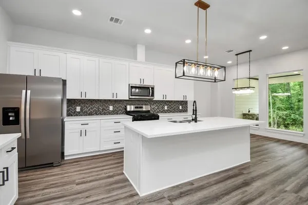 a kitchen with kitchen island white cabinets and stainless steel appliances
