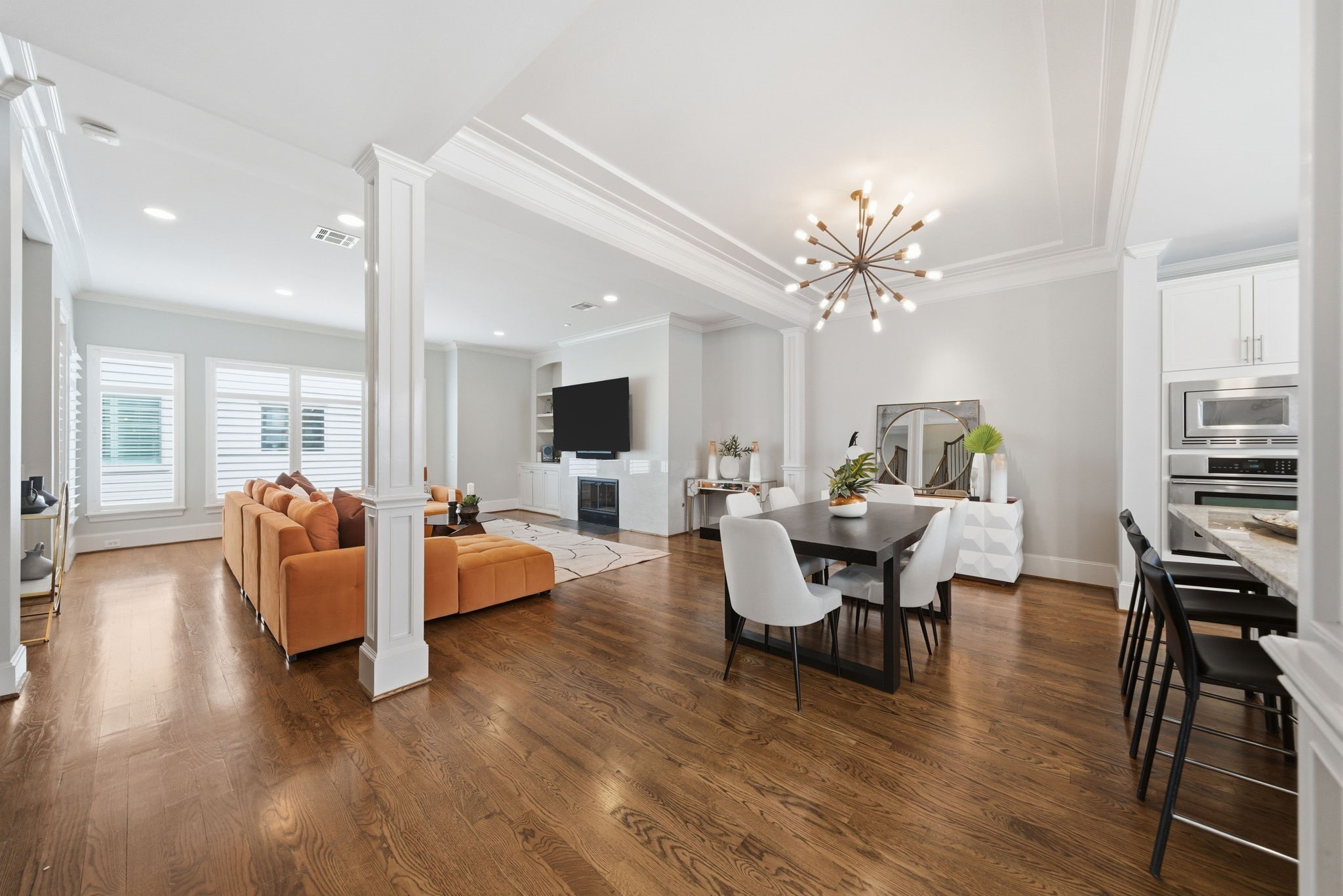 4915 Chenevert Street Houston, TX 77004 - Photo 12 of 41 Elegant formal dining area showcases hardwood flooring, designer lighting, and crisp millwork, seamlessly connecting to the open living room and kitchen. The contemporary layout is ideal for effortless entertaining, creating a warm, inviting atmosphere for both everyday dining and memorable gatherings.
