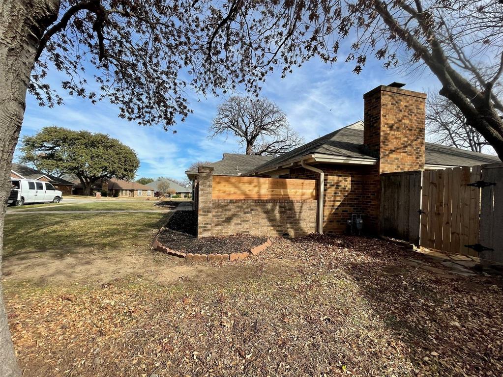2109 Oakmeadow Street Bedford, TX 76021 - Photo 29 of 31 View of side of property featuring a gate, brick siding, and a chimney
