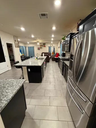 a living room with stainless steel appliances kitchen island granite countertop a sink and cabinets