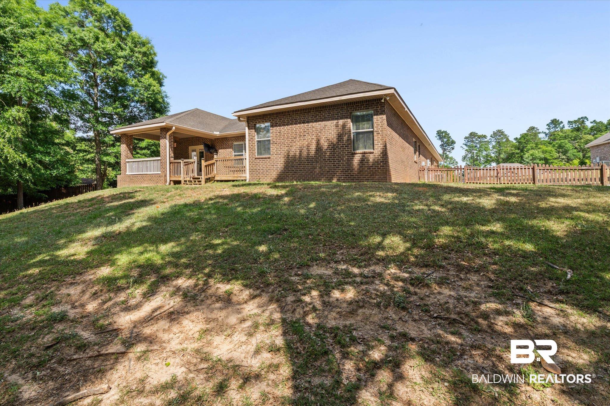3739 Whitestone Drive Semmes, AL 36575 - Photo 22 of 25 Spacious rear yard featuring an elevated brick exterior, covered patio, wooden deck, and partial privacy fencing