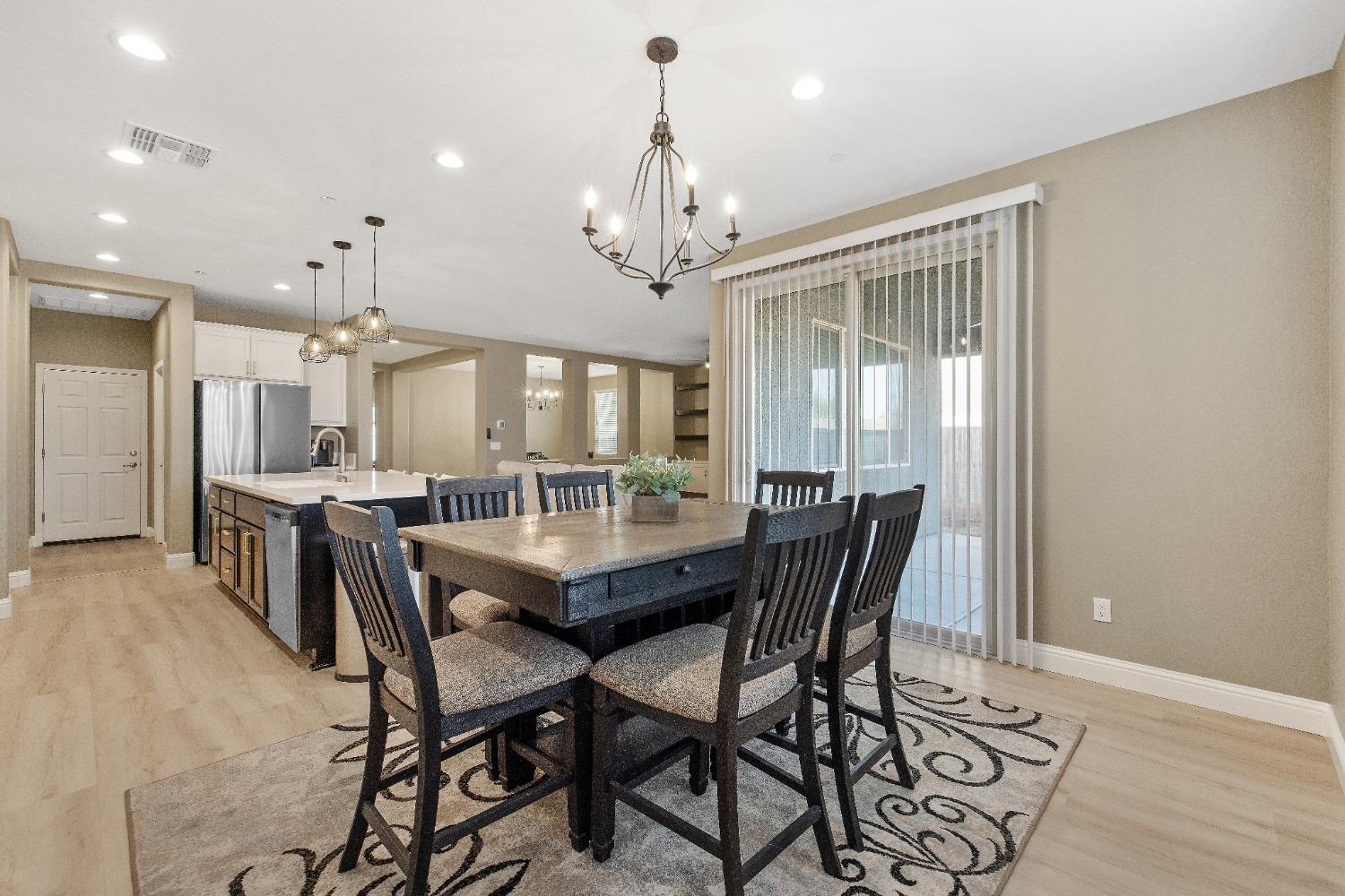 1210 Ridge Creek Estates Way Dinuba, CA 93618 - Photo 30 of 50 a dining room with wooden floor a chandelier a wooden table and chairs