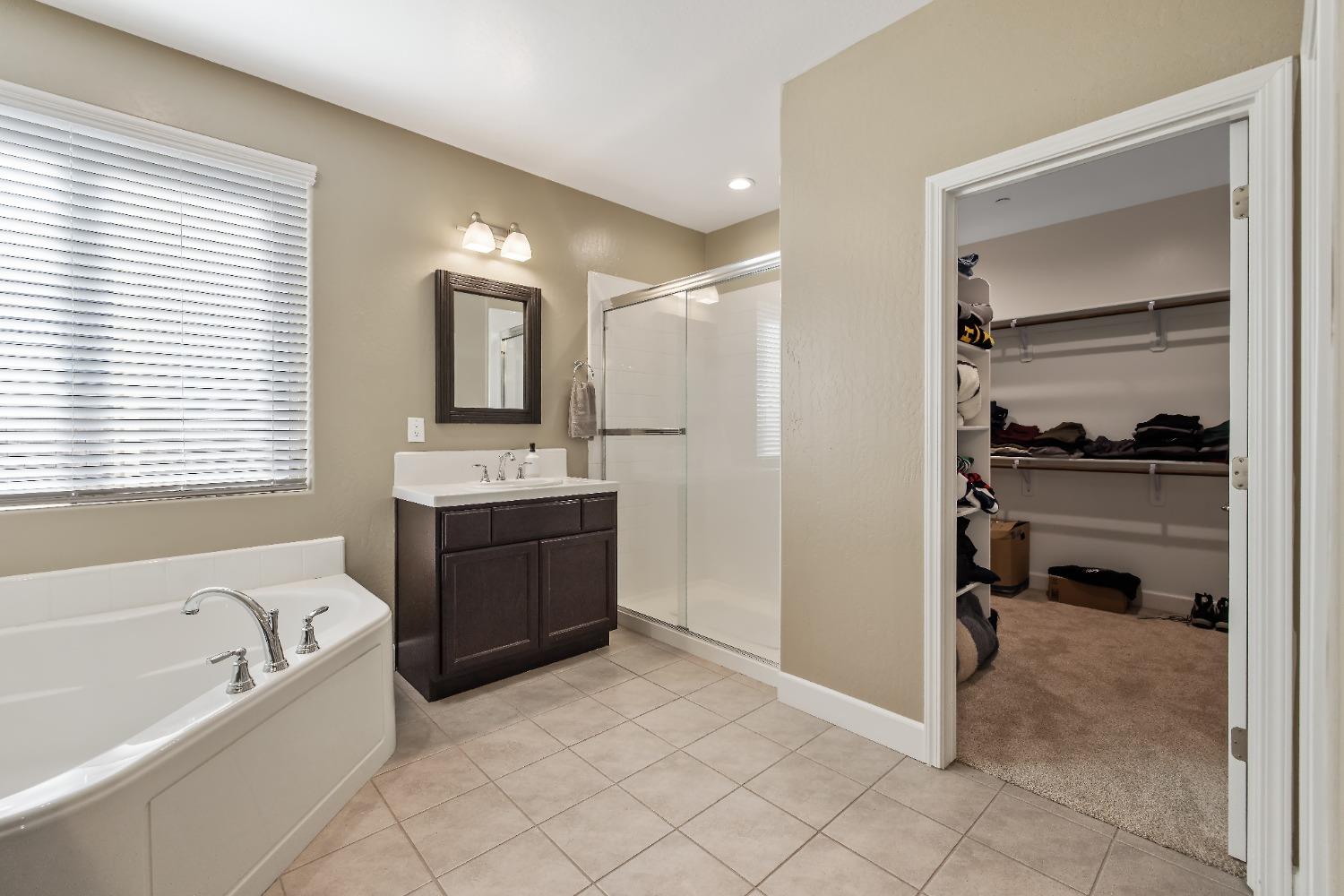 1210 Ridge Creek Estates Way Dinuba, CA 93618 - Photo 34 of 50 a bathroom with a tub a double vanity sink and mirror