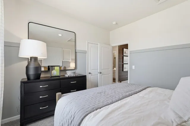 a bedroom with a bed and a lamp on dresser